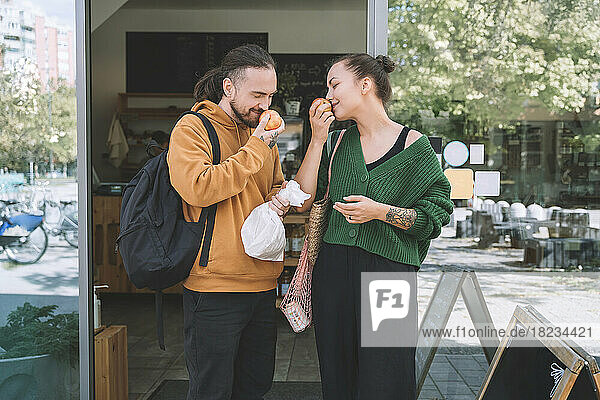 Couple smelling apples standing outside zero waste shop