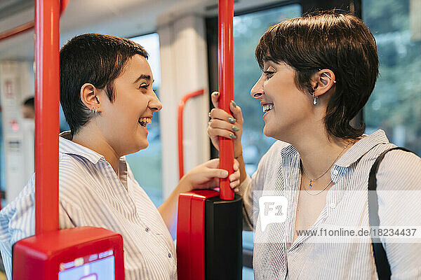 Happy lesbian couple talking to each other in bus