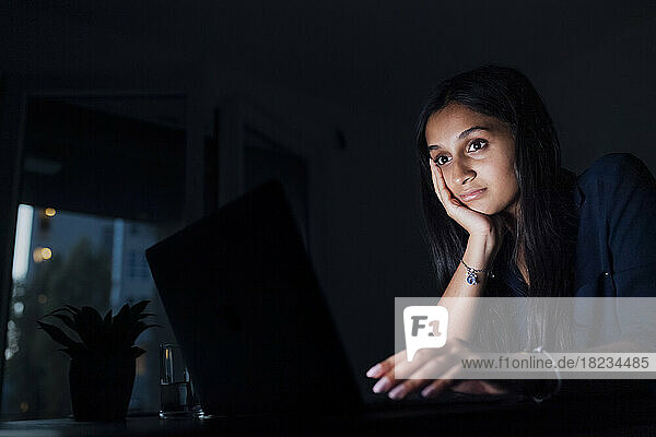 Woman with head in hand looking at laptop