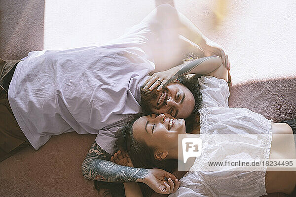 Happy romantic hipster couple lying on bed at home