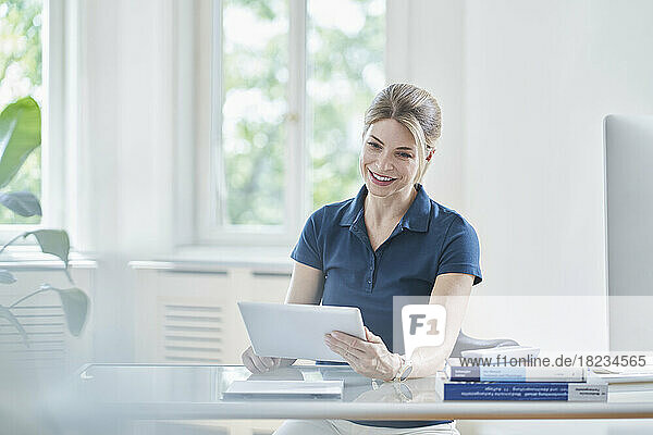 Happy female doctor using digital tablet PC at desk