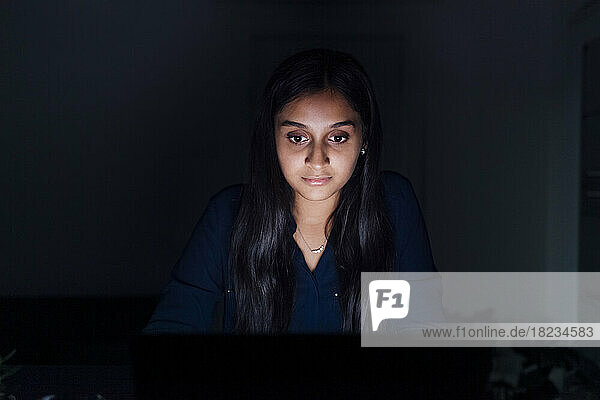 Illuminated young woman in dark room