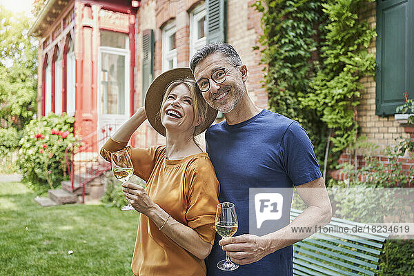 Happy mature man and woman holding wineglasses in back yard
