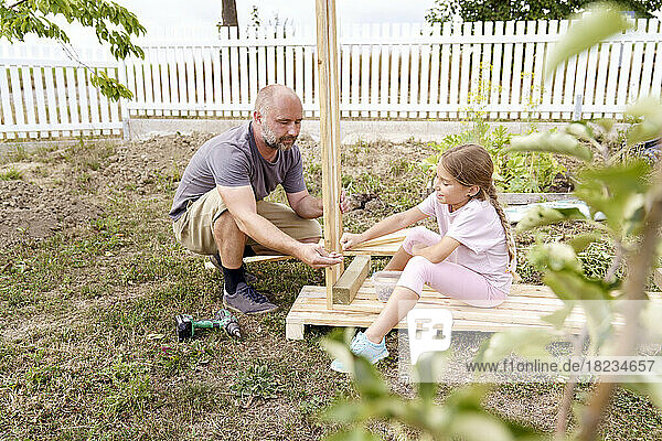 Father and daughter making raised bed in back yard