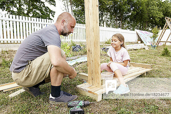 Smiling daughter with father making raised bed in back yard