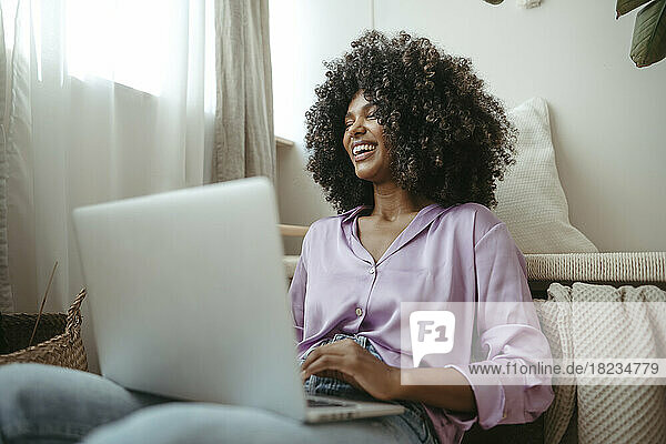 Cheerful young woman with laptop in living room