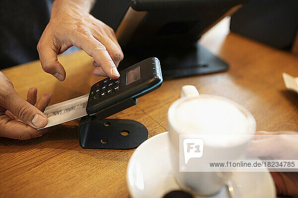 Hände der Kassiererin  die den Kartenautomaten am Café-Schalter benutzt