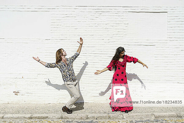 Flamenco dancers performing in front of white wall on sunny day