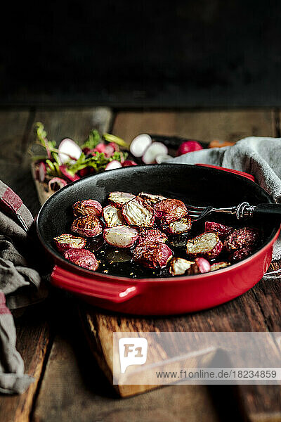 Freshly baked radishes in casserole dish at table