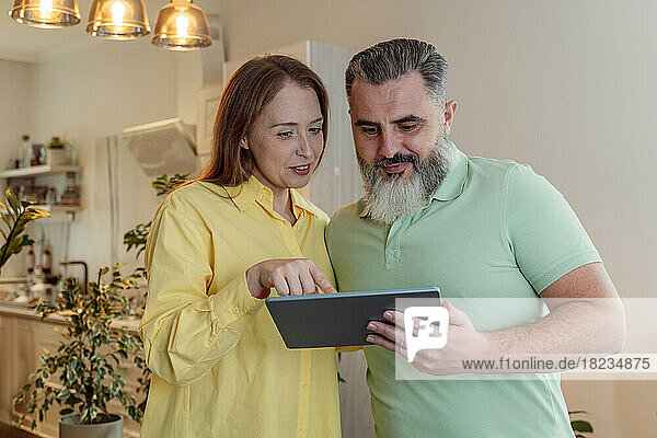 Couple sharing tablet PC standing at home