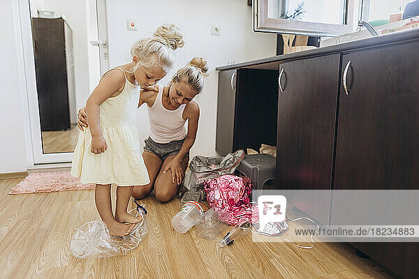 Mother and daughter collecting plastic trash in the kitchen
