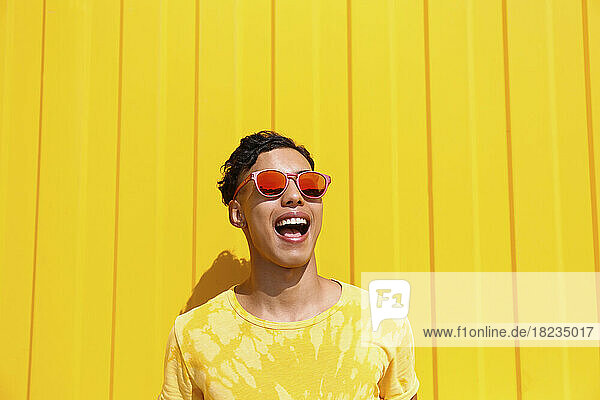 Happy young man screaming in front of yellow wall