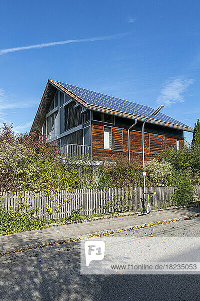 Germany  Bavaria  Munich  Electric push scooter left in front of modern passive house equipped with solar panels