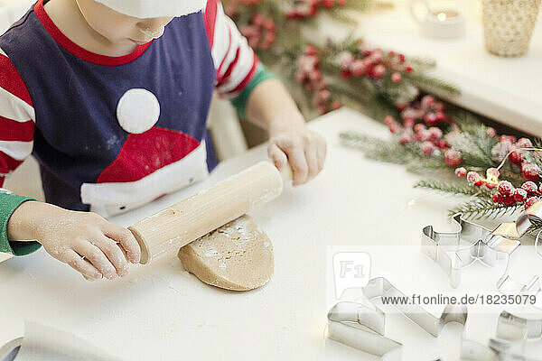 Boy rolling gingerbread dough at kitchen counter