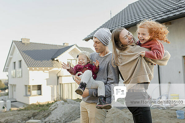 Mother and father carrying daughters outside house