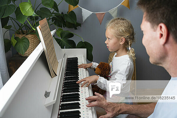 Mädchen liest Noten und spielt zu Hause Klavier