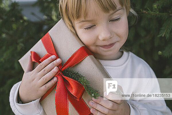 Girl with eyes closed holding Christmas gift box