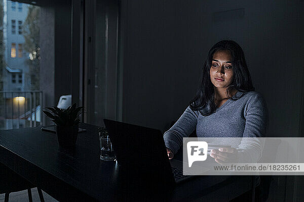 Woman holding credit card doing online shopping through laptop at home