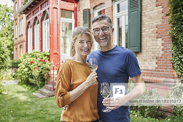 Happy couple holding wineglasses in garden