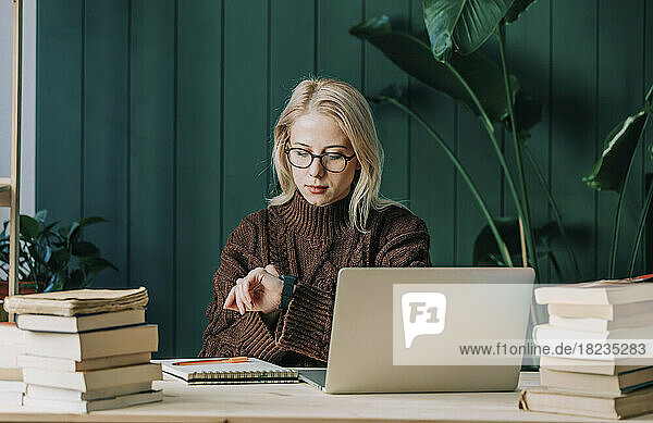 Geschäftsfrau überprüft die Zeit auf einer Smartwatch im Heimbüro