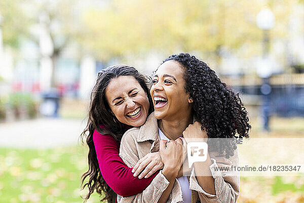 Cheerful woman hugging friend in park