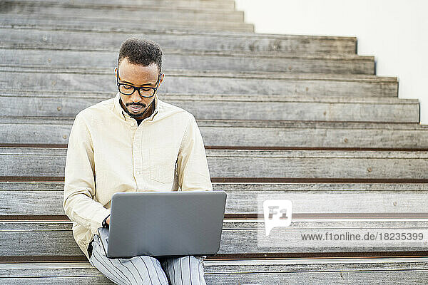 Freelancer using laptop sitting on steps