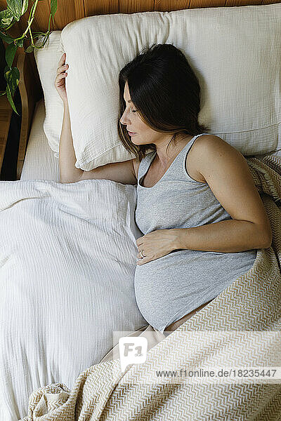 Schwangere reife Frau schläft zu Hause im Bett
