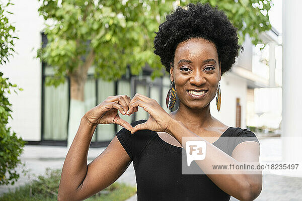 Smiling woman making heart gesture with hands