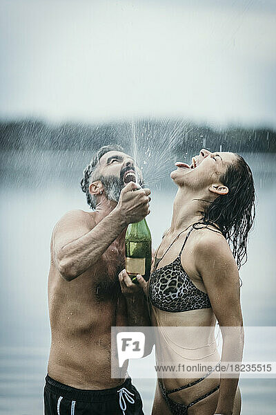 Fröhliches Paar feiert mit Champagner im See