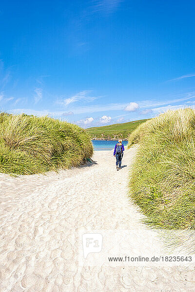 Großbritannien  Schottland  Wanderin  die zwischen den grasbewachsenen Dünen von Scousburgh Sands spaziert