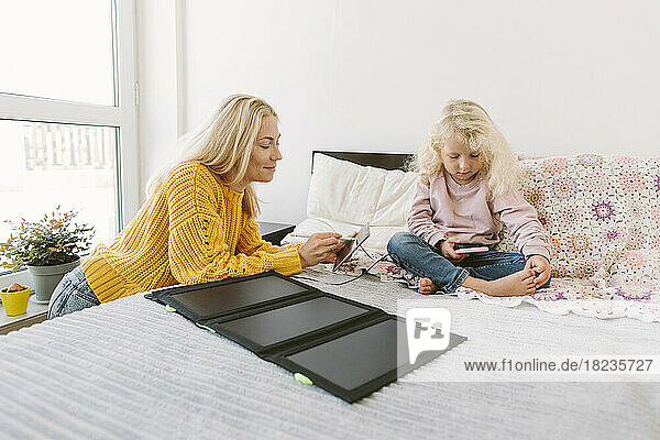 Lächelnde Mutter benutzt Tablet-PC mit Solarbatterieladegerät auf dem Bett