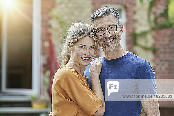 Happy woman embracing smiling man in front of house