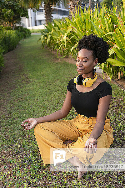 Smiling woman meditating with eyes closed in park
