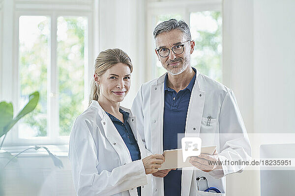 Smiling doctors standing with tablet PC at medical practice
