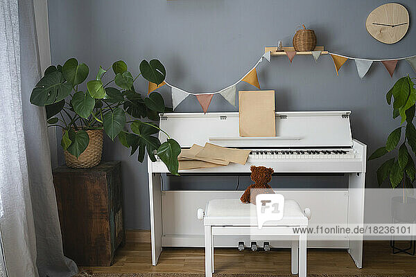 Teddy bear on seat by piano at home