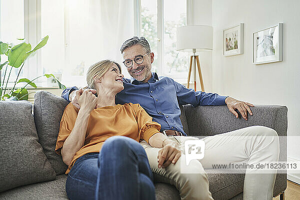 Smiling couple holding hands on sofa at home