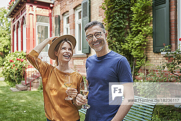 Glücklicher Mann und Frau halten Weingläser im Garten
