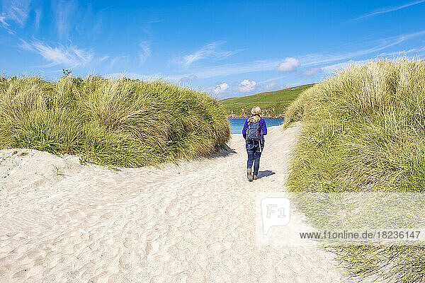 Großbritannien  Schottland  Wanderin  die zwischen den grasbewachsenen Dünen von Scousburgh Sands spaziert