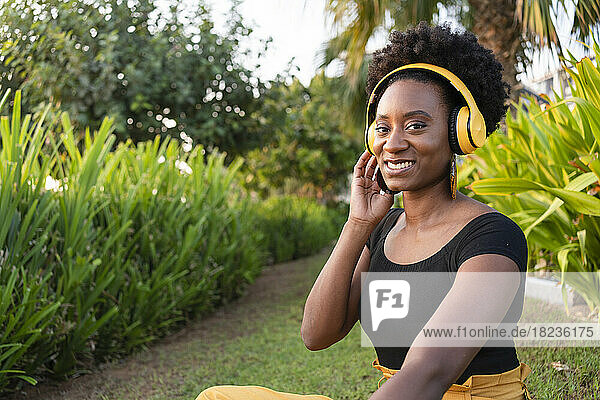 Happy woman wearing headphones listening to music in park