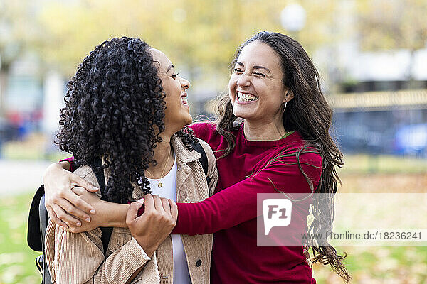 Cheerful woman embracing friend in park
