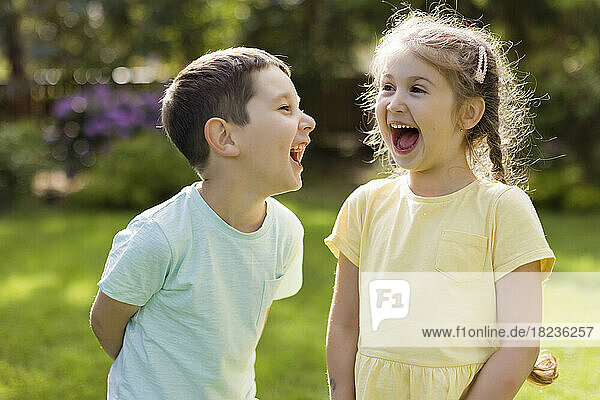 Cheerful girl with brother standing in back yard