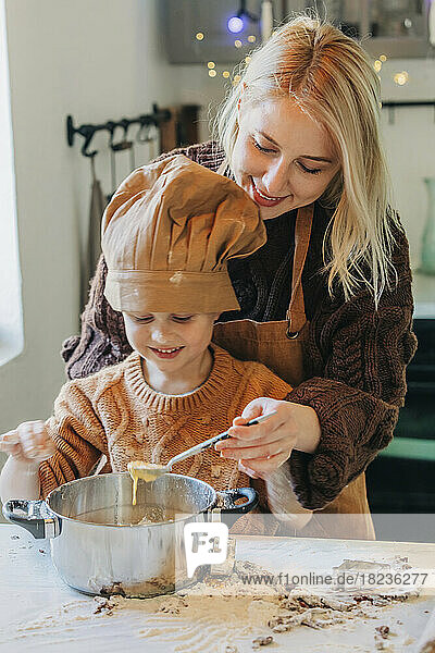 Happy mother and son preparing cookies at home