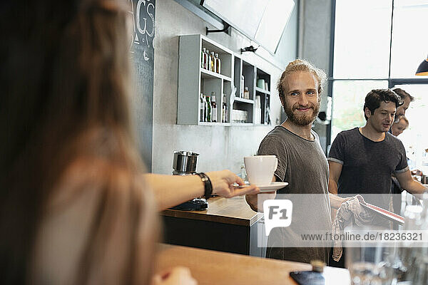 Barista serving coffee to customer in cafe