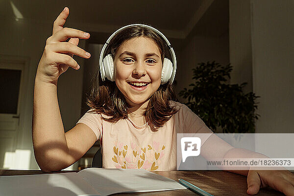 Happy girl wearing wireless headphones sitting at desk