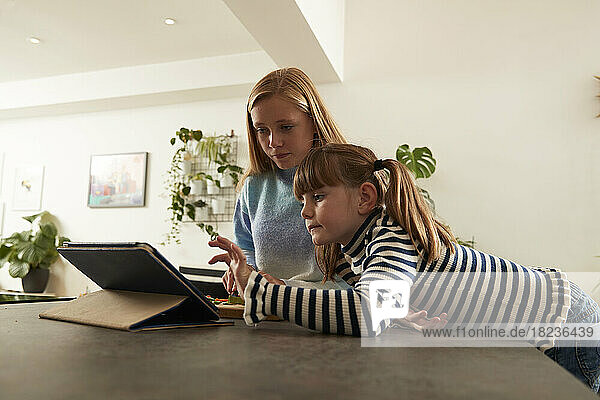Girl with sister using tablet PC at home