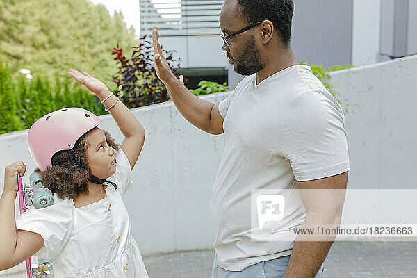 Father giving high-five to daughter wearing helmet