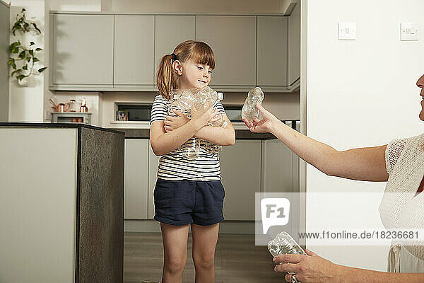 Mother and daughter recycling plastic bottles at home
