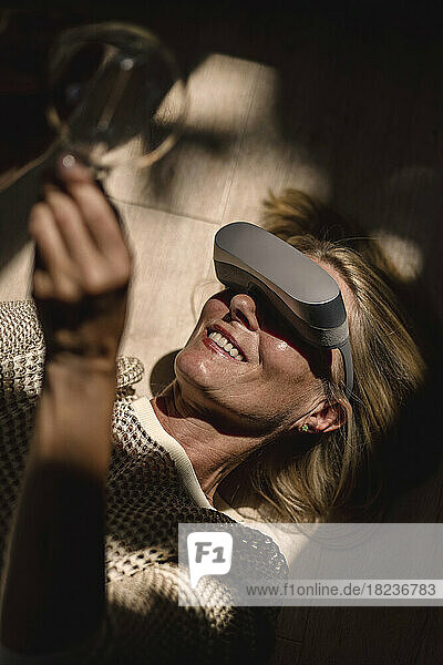Happy woman wearing VR glasses holding light bulb with sunlight on face