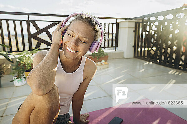 Glückliche Frau  die auf der Terrasse Musik mit Kopfhörern hört