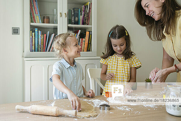 Happy woman with girls preparing cookies at home